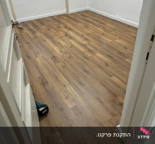 רצפת פרקט חדשה בחדר ריק עם חלון ודלת